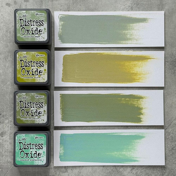 Four 'Distress Oxide' ink pads by Tim Holtz with color swatches on a gray background.