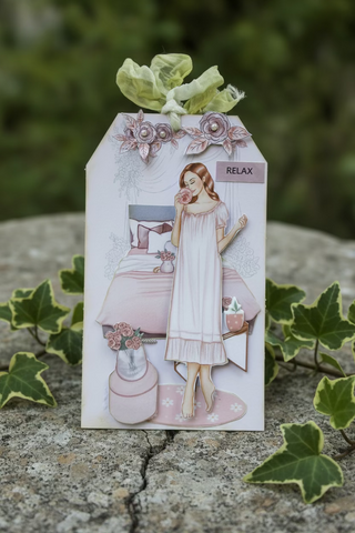 Decorative paper cutout of a woman in a nightgown with floral elements on a textured surface.