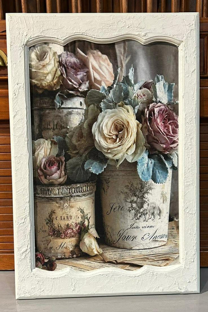 Decorative wall art with flowers and vintage-style jars in a white frame.